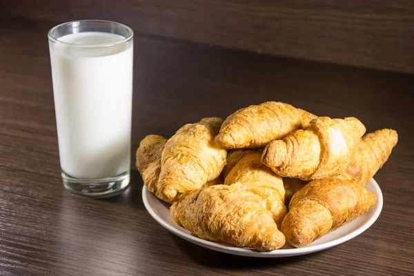 Egy pohár tej és friss croissant fából készült asztalon — Stock Fotó