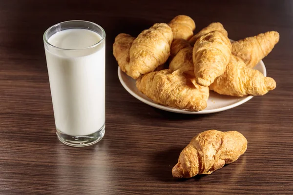 Glass of milk and fresh croissants on wooden table — Stock Photo, Image
