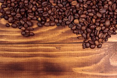 Ahşap arka planda kavrulmuş kahve çekirdekleri.