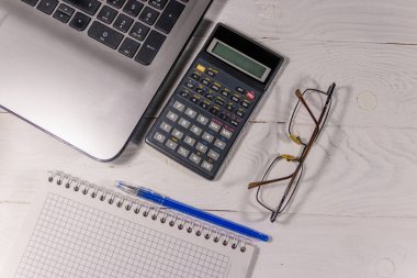 Beyaz ofis büro dizüstü bilgisayar, hesap makinesi, not defteri, gözlük ve kalem