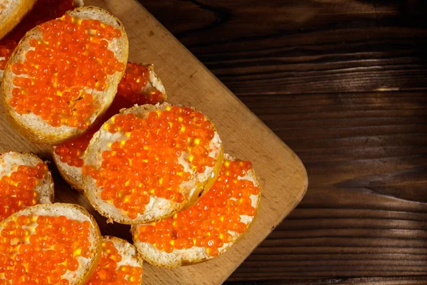 Sanduíches com manteiga e caviar vermelho na mesa de madeira — Fotografia de Stock