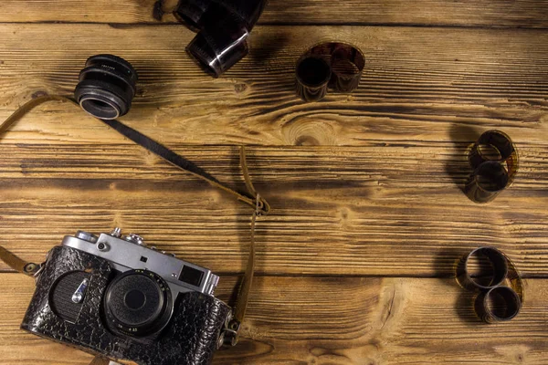 Ретро фотокамера с фотопленкой и объективом на деревянном столе — стоковое фото