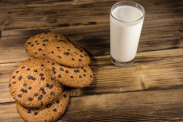 Chocolate chip cookies and glass of milk on wooden table — Stock Photo, Image