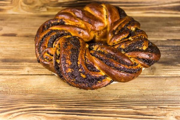 Zoet broodje met maanzaad op houten tafel — Stockfoto