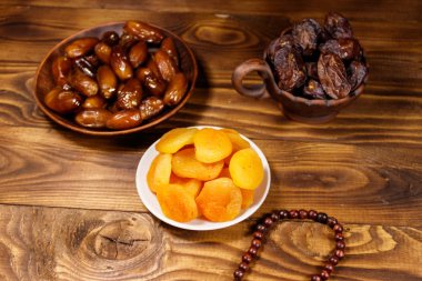 Ahşap masa üzerinde ahşap Tespihler ile kurutulmuş kayısı ve tarihleri meyve