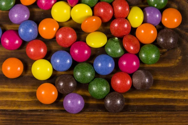 Bonbons colorés en forme de bouton remplis de chocolat sur une table en bois — Photo