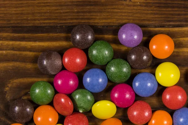 Coloridos caramelos en forma de botón llenos de chocolate en la mesa de madera — Foto de Stock