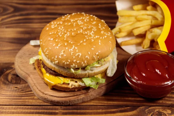 Leckerer großer Hamburger mit Pommes und Ketchup auf Holztisch — Stockfoto