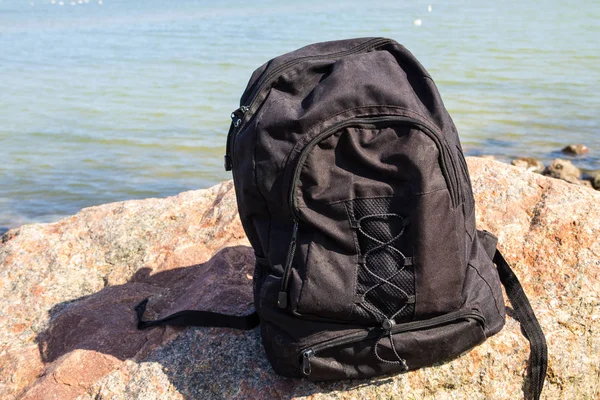 Рюкзак на скале на фоне морского берега — стоковое фото