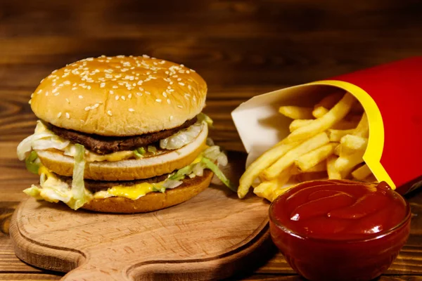 Leckerer großer Hamburger mit Pommes und Ketchup auf Holztisch — Stockfoto