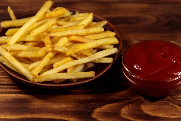 Pommes frites med ketchup på träbord — Stockfoto