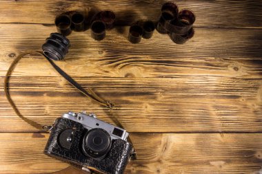 Ahşap masanın üzerinde fotoğraf makinesi ve lens olan eski fotoğraf makinesi.