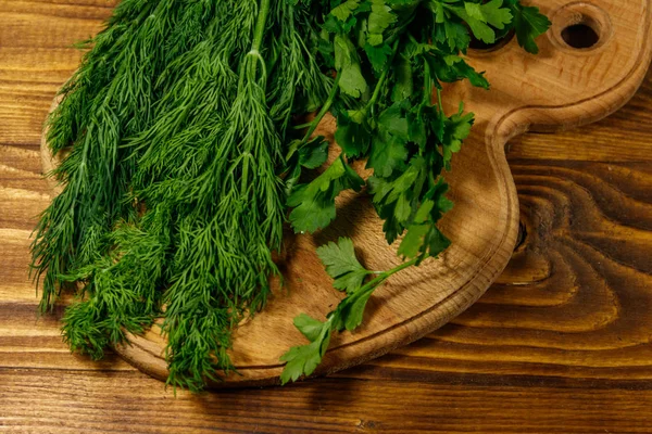 Fresh green dill and parsley on cutting board on wooden table — Stock Photo, Image