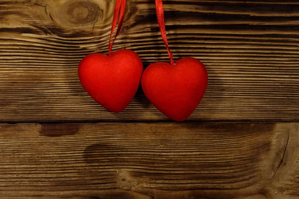 Два червоних серця, що звисають над дерев'яним тлом — стокове фото