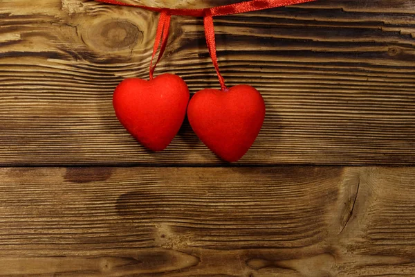 Dos corazones rojos colgando sobre fondo de madera — Foto de Stock