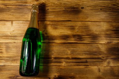 Ahşap arka plan üzerinde şampanya şişesi. Üstten görünüm, kopya alanı