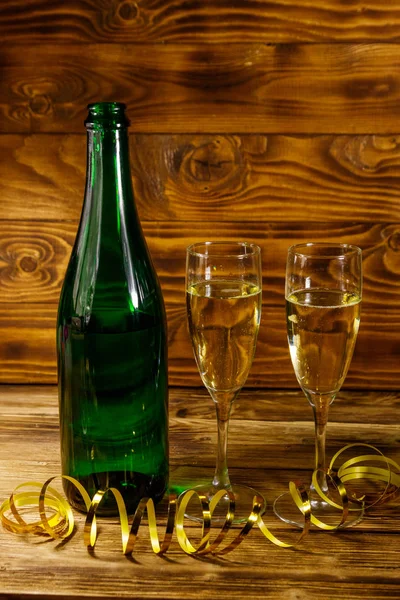 Geopende champagnefles en twee glazen champagne op houten tafel — Stockfoto