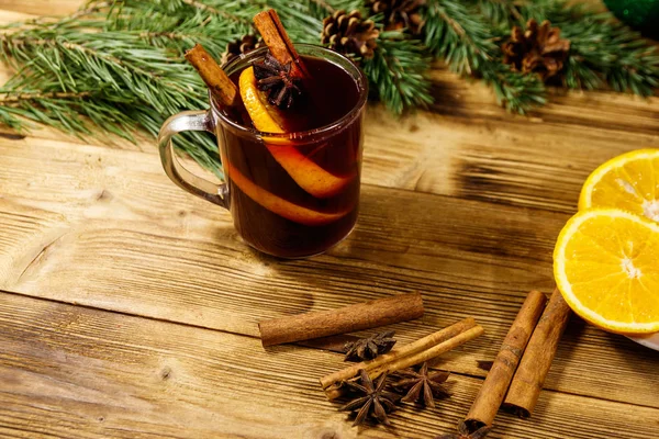 Christmas mulled wine with spices and fir tree branches and cones on wooden table — Stock Photo, Image