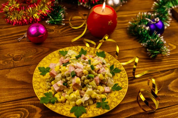 Sabrosa ensalada festiva, decoración de Navidad y vela en la mesa de madera — Foto de Stock