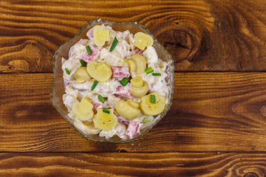 Ahşap masada marine mantar, sosis, soğan ve mayonez ile patates salatası