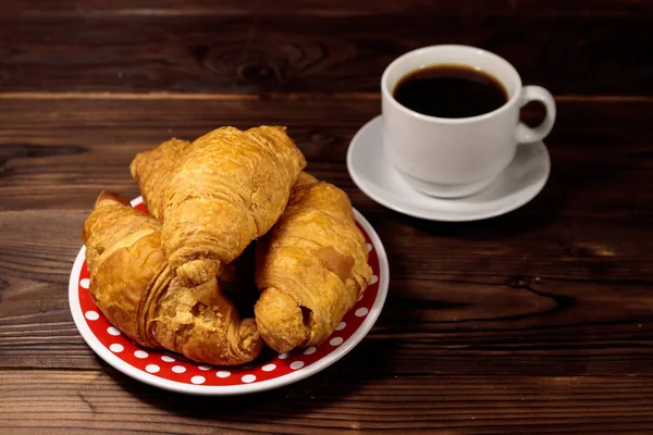 Tasse de café et assiette avec croissants frais sur table en bois — Photo