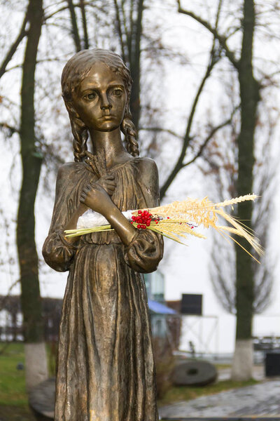Sculpture of hungry young girl with ears of wheat in their hands