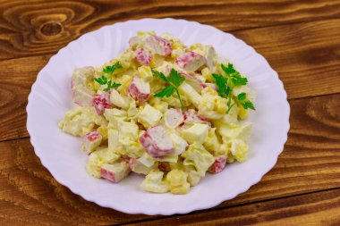 Yengeç saplı salata, tatlı mısır, Çin lahanası, yumurta ve mayonez ahşap masada.