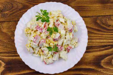 Yengeç saplı salata, tatlı mısır, Çin lahanası, yumurta ve mayonez ahşap masada.