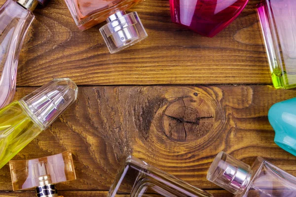 Diferentes botellas de perfume en el fondo de madera. Vista superior, espacio de copia —  Fotos de Stock