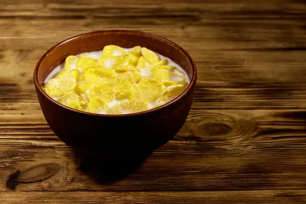 Cornflakes med mjölk i en skål på träbord — Stockfoto