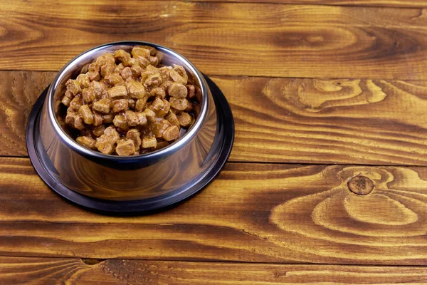 Консервы для кошек или собак в металлической миске на деревянном полу — стоковое фото