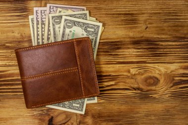 Kahverengi deri cüzdan ve ahşap masada Amerikan doları. Üst görünüm