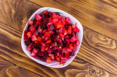 Traditional russian salad vinaigrette with beetroot, carrot, potato, onion and pickled cucumbers on wooden table. Top view clipart