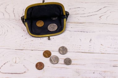 Beyaz ahşap arka planda birkaç bozukluk bulunan eski bozuk para çantası.. 