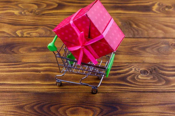 Carrito de compras con caja de regalo grande sobre fondo de madera —  Fotos de Stock