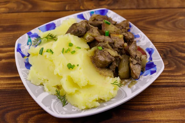 Mashed potatoes with stewed chicken liver with apple and onion on wooden table — Stock Photo, Image