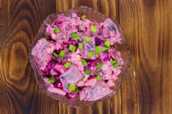 Smakelijke salade met haring, rode biet, eieren, ui en mayonaise op houten tafel — Stockfoto