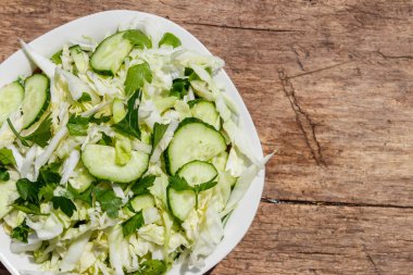 Bahar vegan salata lahana, salatalık, yeşil soğan ve maydanoz ahşap masa üzerinde. Üstten görünüm