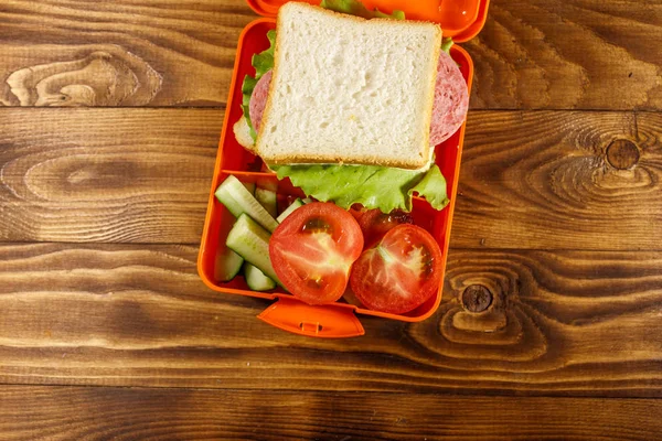 Skolan matlåda med smörgås och färska grönsaker på träbord. Ovanifrån — Stockfoto