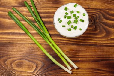 Ekşi krema ve ahşap masa üzerinde yeşil soğan. Üstten görünüm