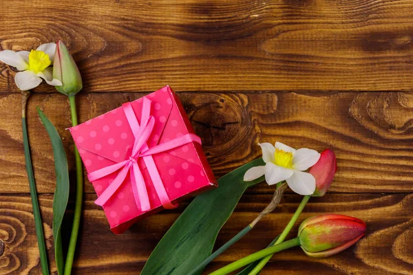 Gift box and bouquet of red tulips and daffodils on wooden background. Concept of Valentine's Day, Women's Day, Mother's Day and Birthday. Top view, copy space Stock Picture