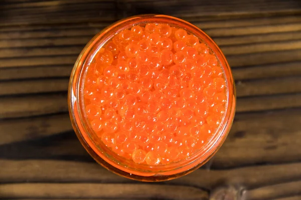 Caviar vermelho em frasco de vidro na mesa de madeira — Fotografia de Stock