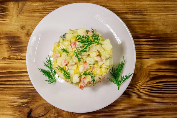 Салат с крабовыми палочками, сладкой кукурузой, огурцом, яйцами и майонезом на деревянном столе. Вид сверху — стоковое фото