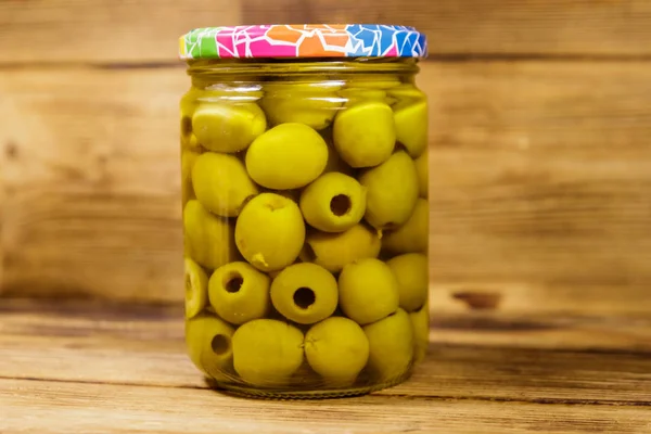 Aceitunas verdes en vinagre en frasco de vidrio sobre mesa de madera —  Fotos de Stock