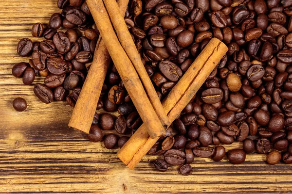 Roasted coffee beans and cinnamon sticks on rustic wooden background. Top view — Stock Photo, Image