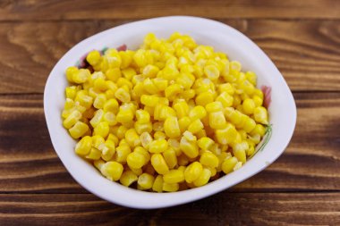 Ahşap masa üzerinde bir kase konserve mısır