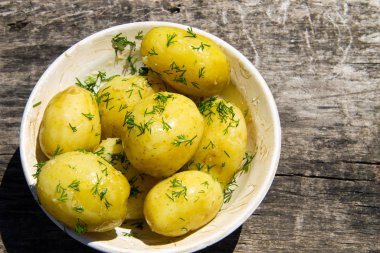 Eski ahşap masada tereyağlı ve dereotlu haşlanmış yeni patates. Üst görünüm