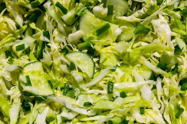 Ensalada vegana de primavera con repollo, pepino, cebolla verde y perejil primer plano. Fondo alimentario —  Fotos de Stock