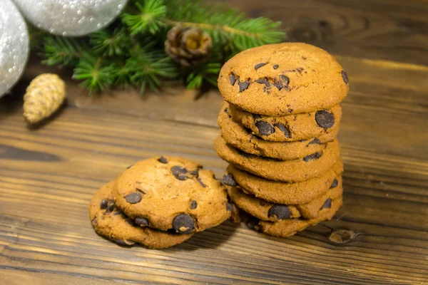 Chocolate chip cookies in front of Christmas decoration on wooden table — Stock Photo, Image
