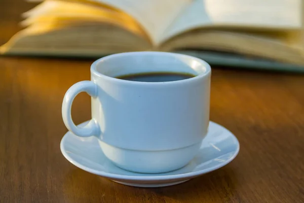 Taza de café y libro sobre mesa de madera — Foto de Stock